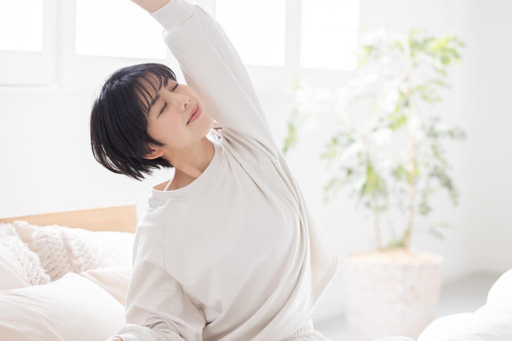 ベッドでストレッチをする女性